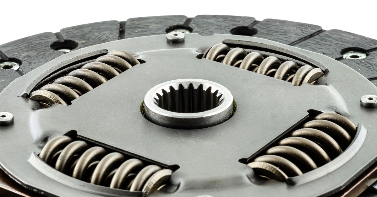 A close-up of a new clutch disc, including the damper springs and friction linings, against a white background.