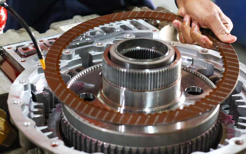 A close-up of a hand installing a clutch friction plate into a transmission assembly for a clutch vehicle.