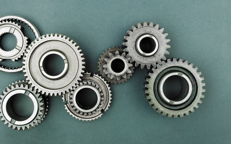 An overhead view of an assembly of six various industrial gear sizes connected together on a grey surface.