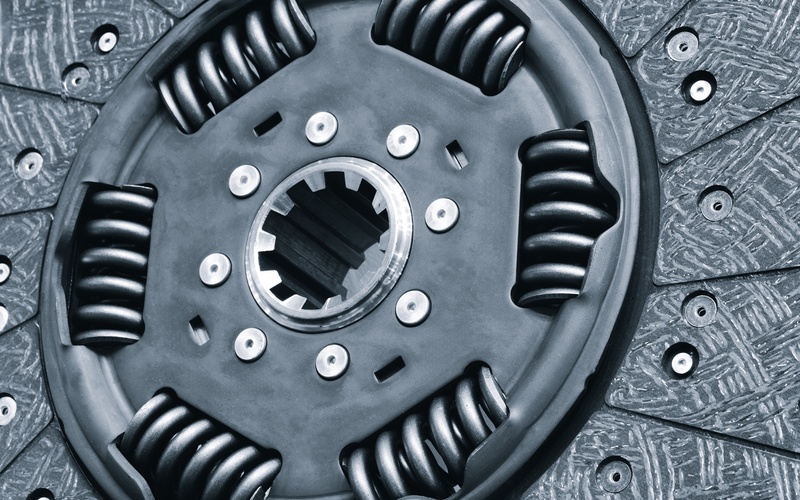 A close-up of a detached steel automotive vehicle clutch, including the steel disc and steel springs.