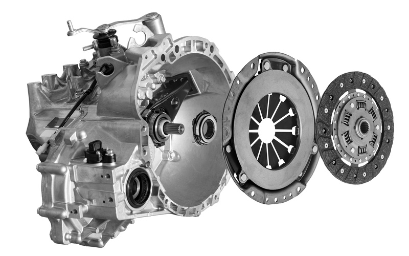 A side view of an automotive clutch disc detached with the clutch basket, bearing, and gearbox against a white background.