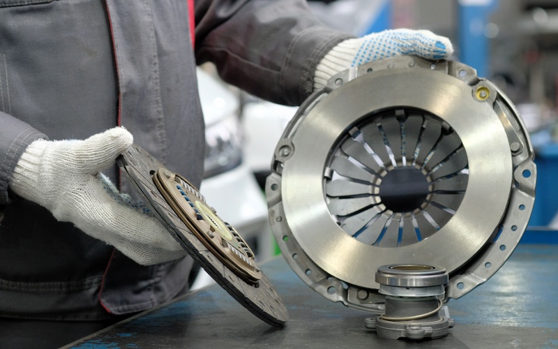 A close-up of a person with white gloves examining a new clutch kit's parts, including the disc and exhaust bearing.