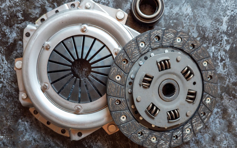 Brand-new clutch components for a manual transmission car, including pressure plate, clutch disc, and release bearing.