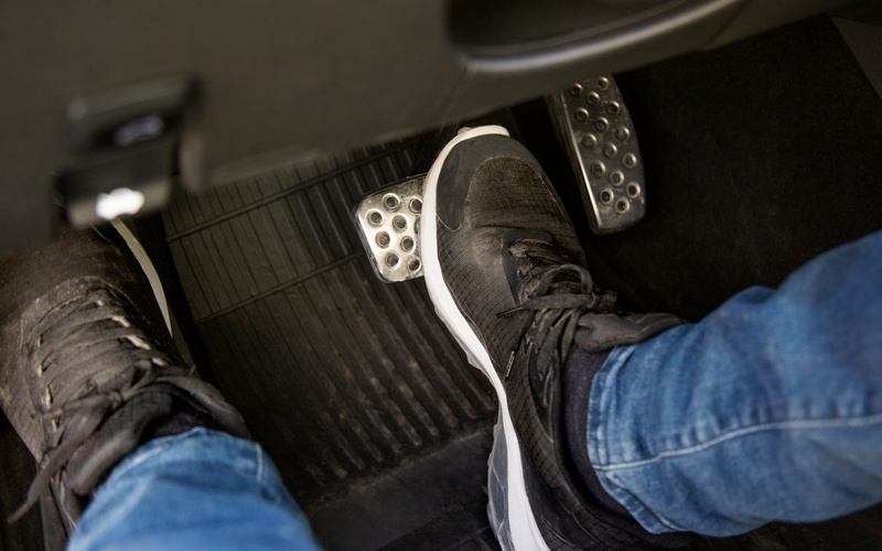 The area underneath the driver's seat of a manual transmission car, with the driver pressing the brake and clutch pedal.