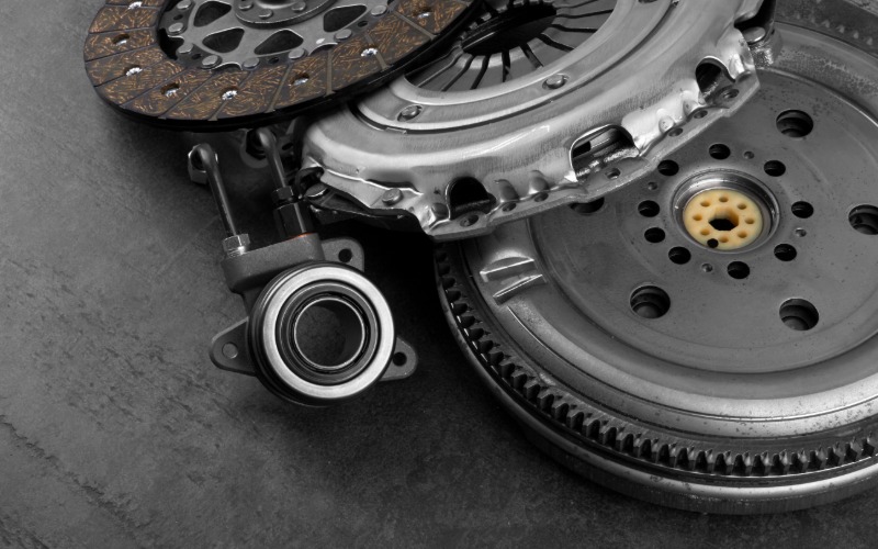 A close-up of a car's clutch components on a table in a pile, including the clutch disc and release bearing.