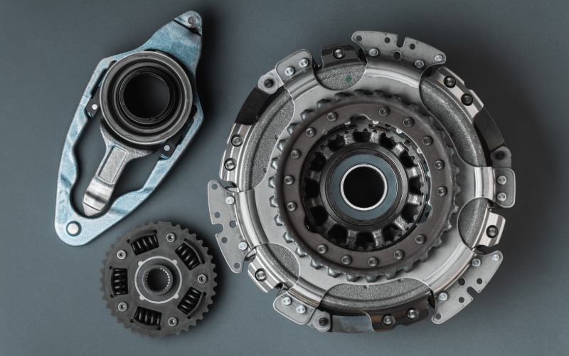 An overhead close-up view of the components of a new clutch kit for an automatic gearbox on a grey surface.