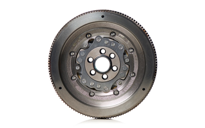 A frontal view of a dual-mass automotive flywheel standing upright and isolated against a white background.