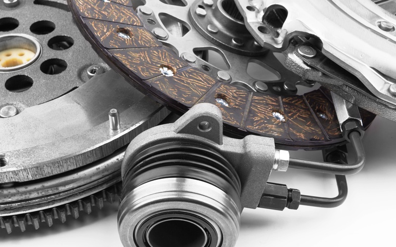 A close-up of various automotive clutch kit components, including the release bearing and clutch disc, on a white surface.