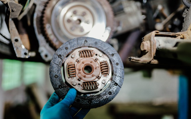 A close-up of the clutch disc and basket of a vehicle detached from the transmission against a black background.
