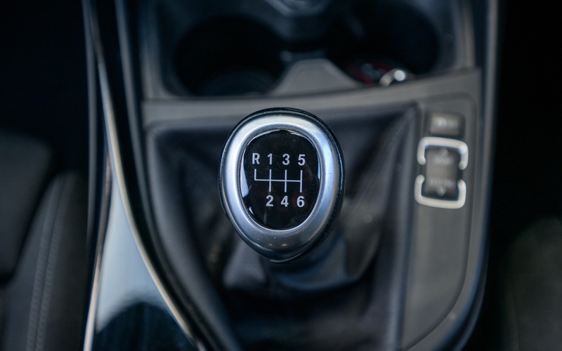 A close-up view from above of the gear stick of a manual transmission vehicle, showing six gears and reverse.