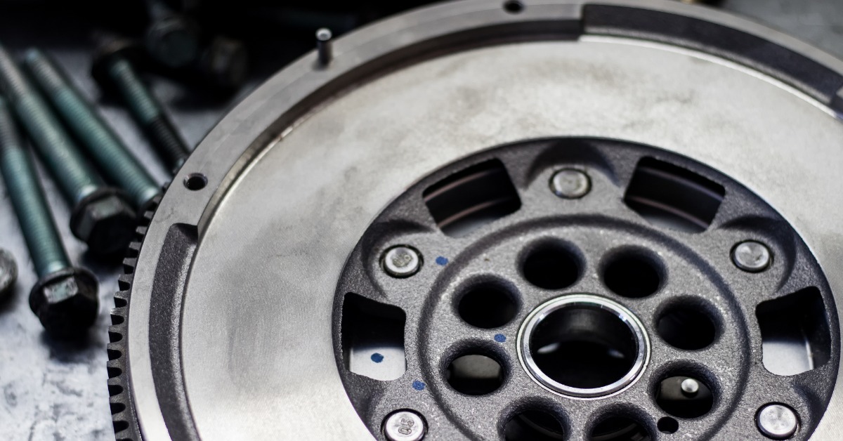 A close-up of the surface of an automotive dual-mass flywheel with the fastener parts in the background.