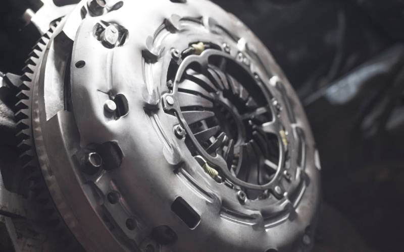 A new, high-performance sport clutch with flywheel for a car. The clutch is in a dark room with a spotlight focused on it.