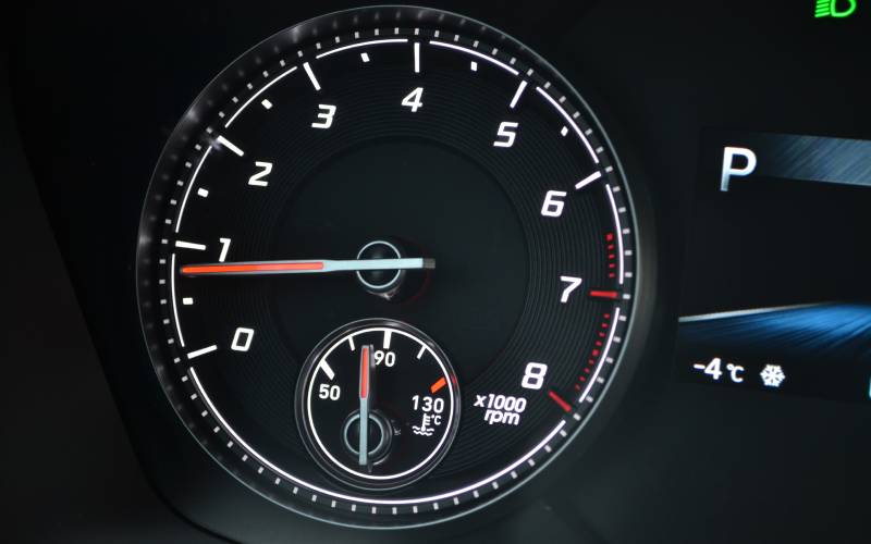 A vehicle's tachometer beside a temperature gauge at close range. The needle on the tachometer approaches 1,000 rpm.