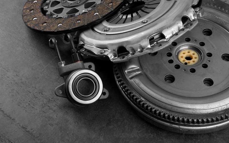 A close-up of a car engine clutch, including the release bearing, clutch plate, and flywheel components stacked together.