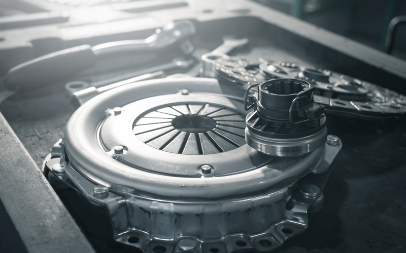 A close-up of a brand-new automotive clutch kit, including a flywheel and release bearing, on a mechanic's table.