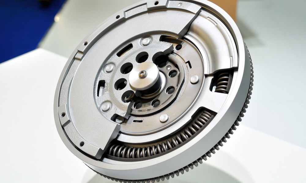 An individual dual mass flywheel displayed with half of the top covering case removed to show the inner components.