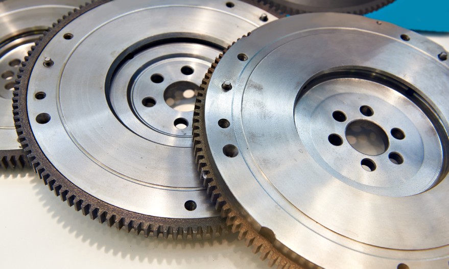 A row of three crankshaft flywheels arranged together on a table and lightly stacked on top of one another.