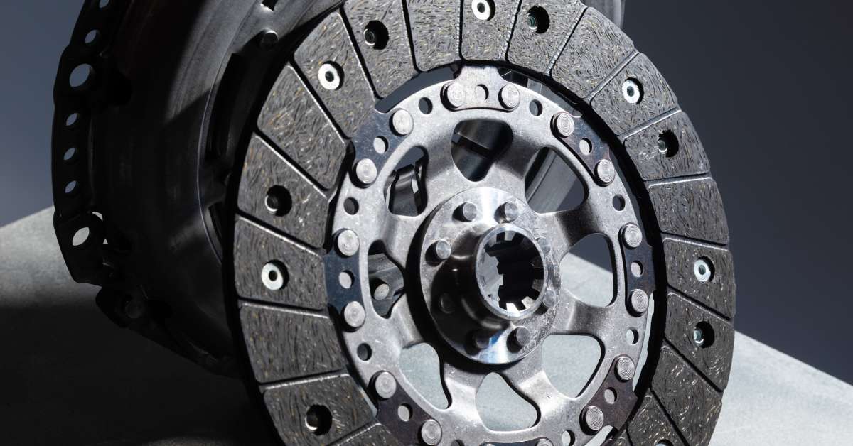 A black clutch disk of a performance clutch kit is propped up for display vertically against another clutch component.